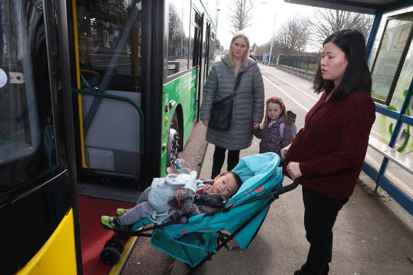 Customers boarding bus at shelter with buggy