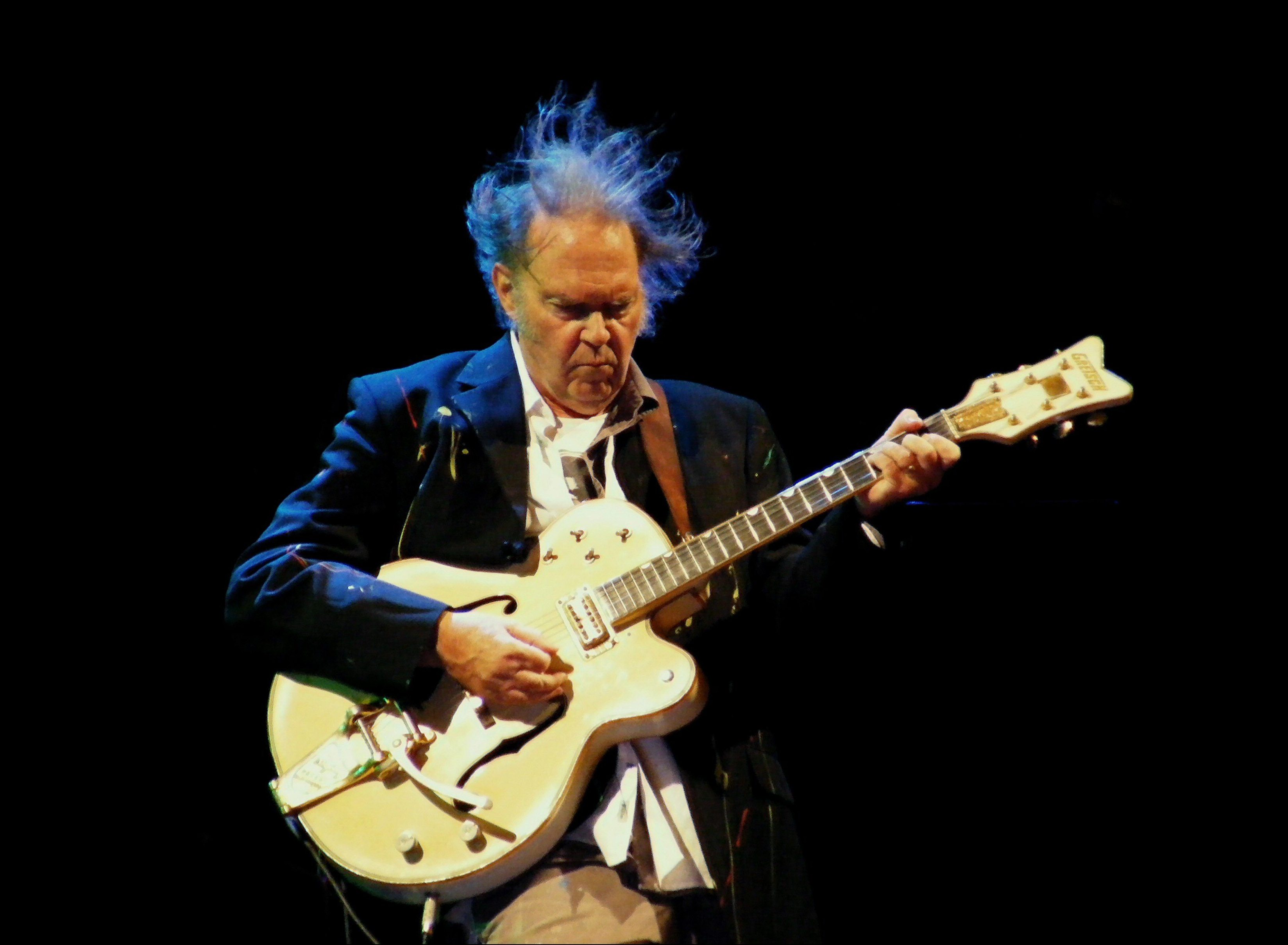 Image of Neil Young on stage playing guitar
