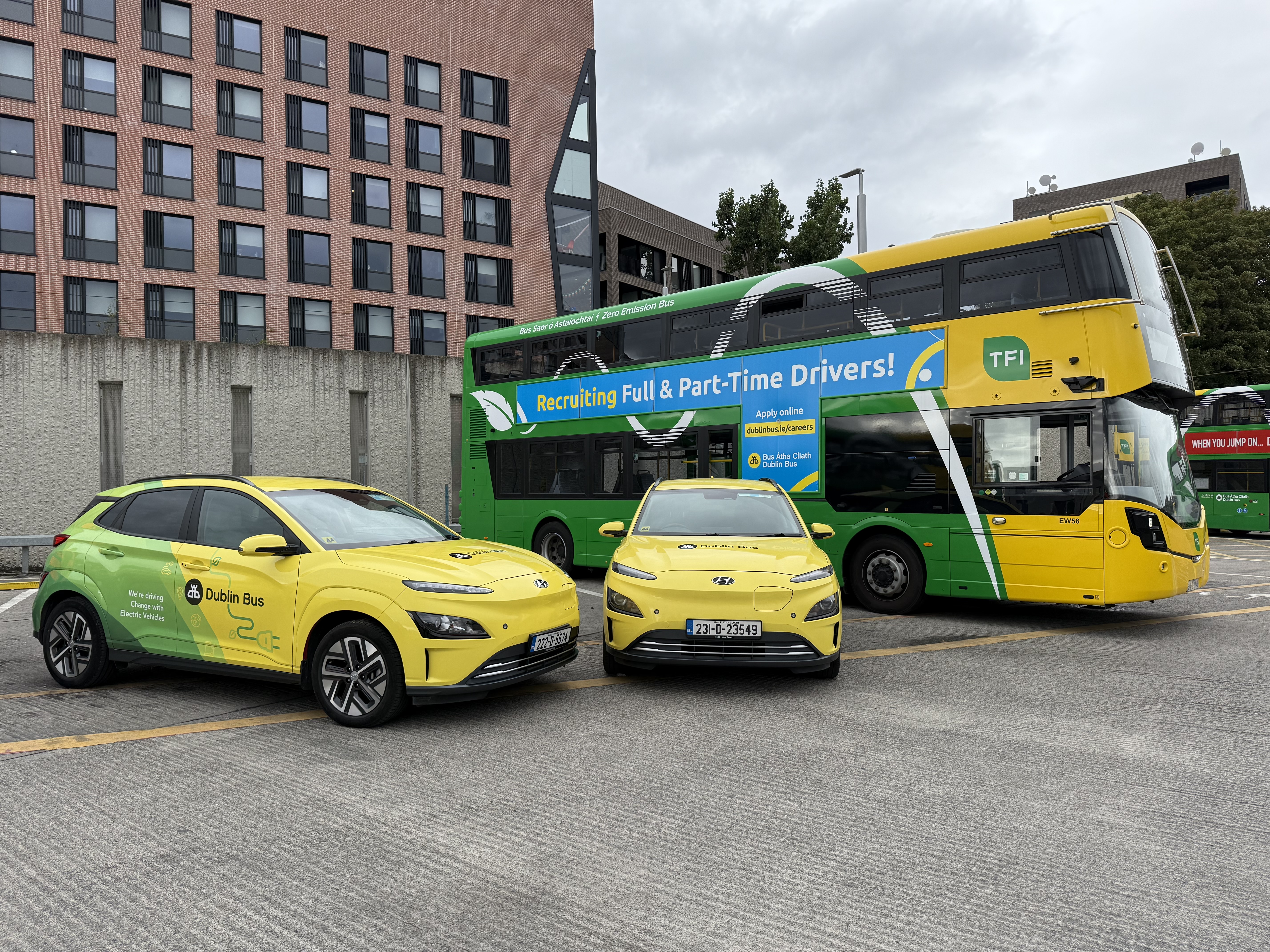 Image of a Green and Yellow Dublin Bus with two Green and yellow Dublin Bus cars parked in front.