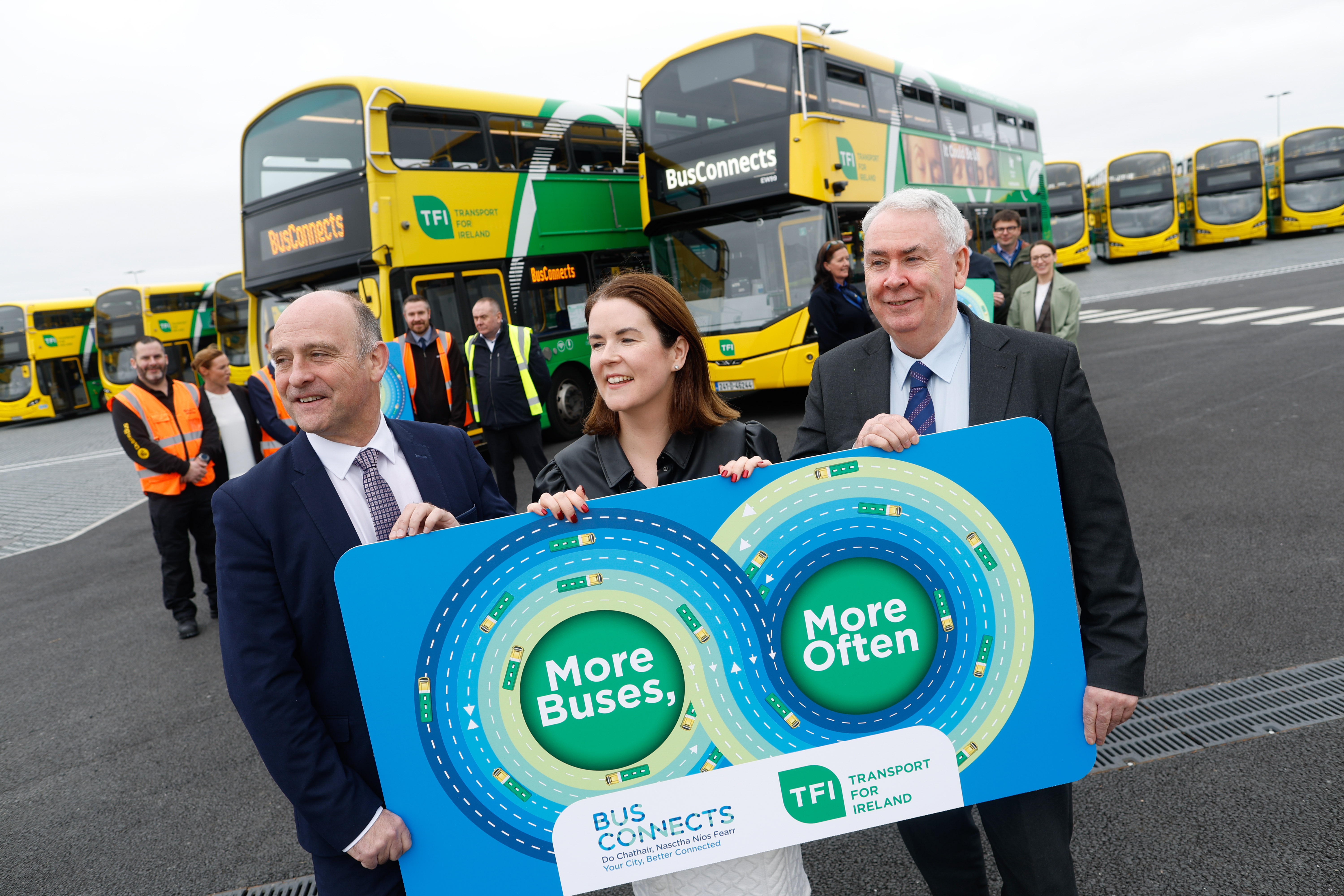 Image of two buses, yellow and green in livery. Bus Connects is displayed on scroll with three people standing in front holding a sign that reads 'More Buses'